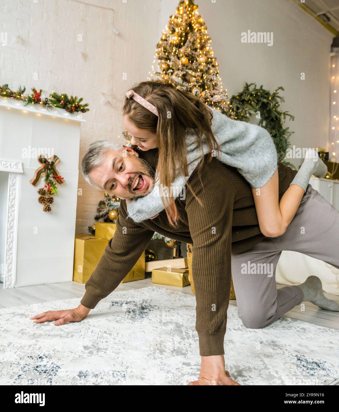 Père donnant à sa fille un tour de piggyback dans un cadre festif de Noël. Joyeux moment en famille. Banque D'Images