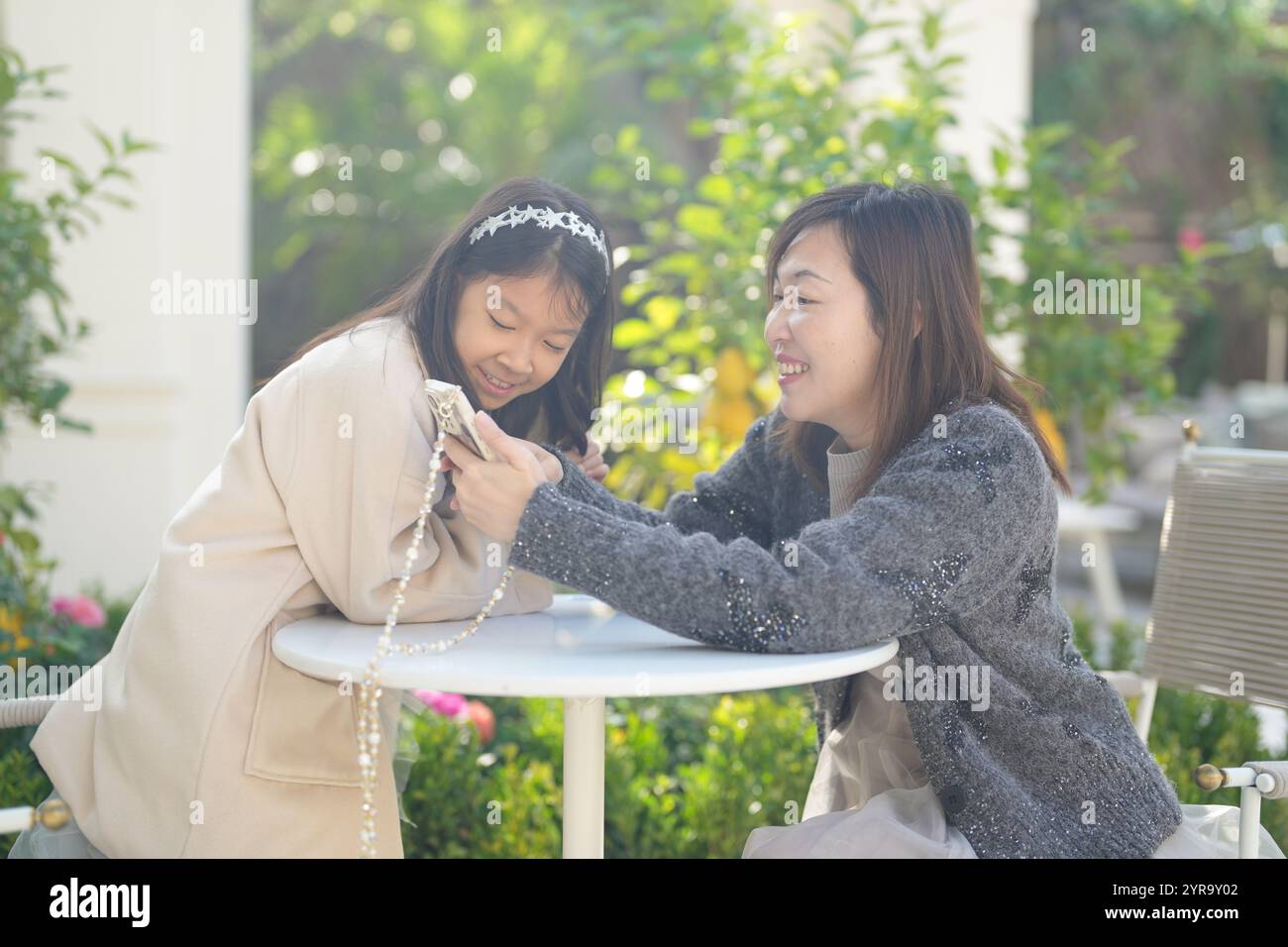 Une femme singapourienne de 40 ans et sa fille de 9 ans regardent leurs smartphones dans un charmant café décoré de Noël dans le centre-ville de Shanghai, en Chine. Banque D'Images