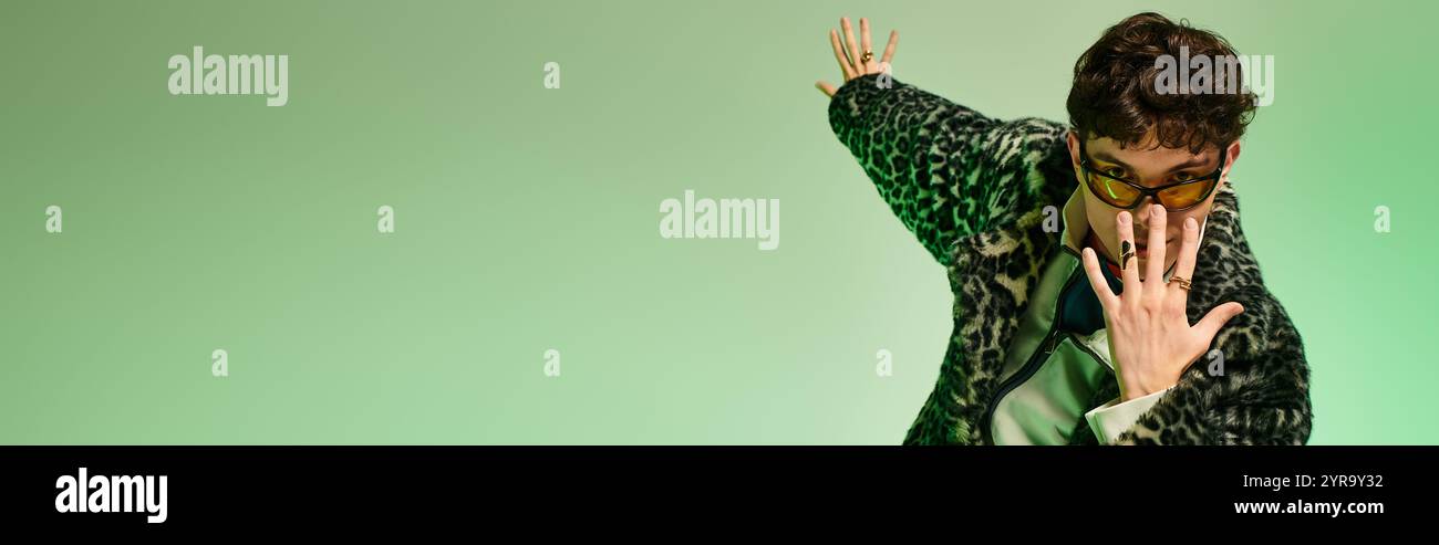 Un homme dapper prend la pose sur un fond coloré, exsudant confiance et style. Banque D'Images