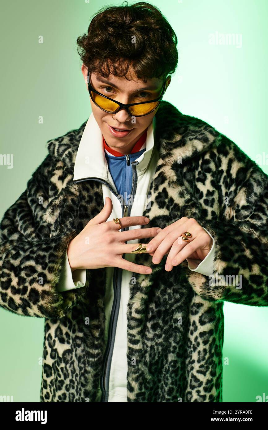 Beau homme affiche un style audacieux avec un manteau chic et des lunettes de soleil, rayonnant charisme et flair. Banque D'Images