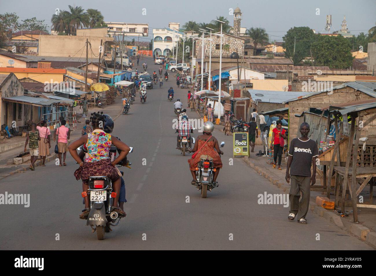 Rue urbaine animée au Togo avec des motos, des piétons et des magasins locaux illustrant la vie quotidienne africaine Banque D'Images