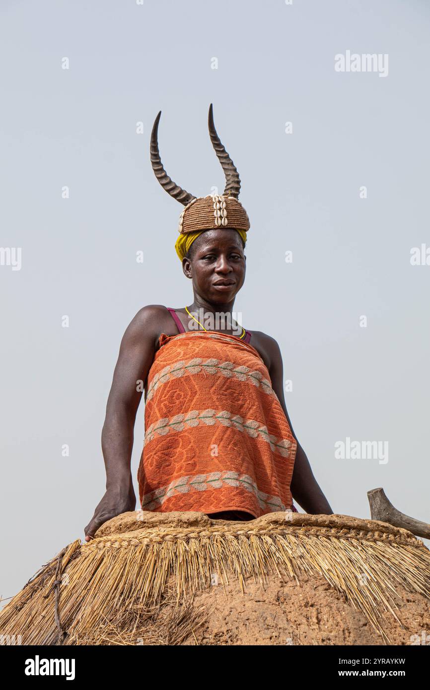 Femme en costume traditionnel avec chapeau corné souriant dans un village rural au Togo Banque D'Images