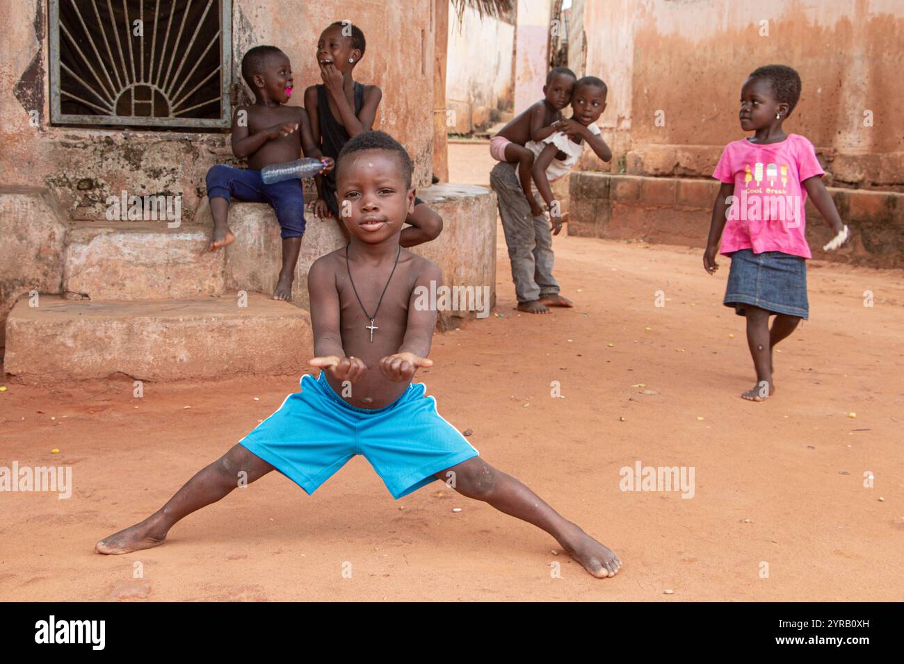 Groupe d'enfants de Togoville jouant sur une rue Sandy au Togo, capturant des moments joyeux d'enfance et l'esprit communautaire africain Banque D'Images