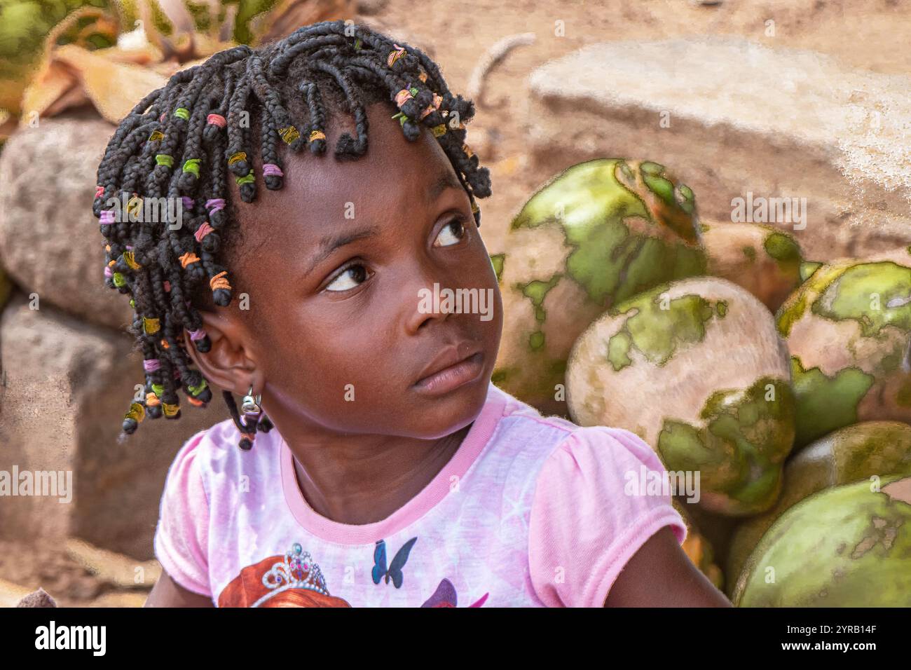 Portrait d'une jeune fille avec des tresses colorées assis parmi des noix de coco fraîches au Togo Banque D'Images