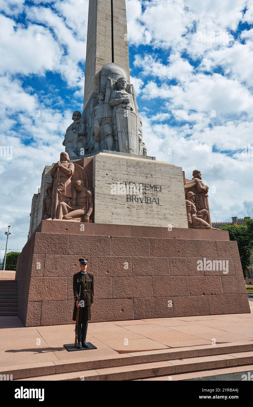 Un soldat en uniforme de cérémonie monte la garde devant un grand monument à Riga, en Lettonie, avec des sculptures complexes et des inscriptions, avec un b. Banque D'Images