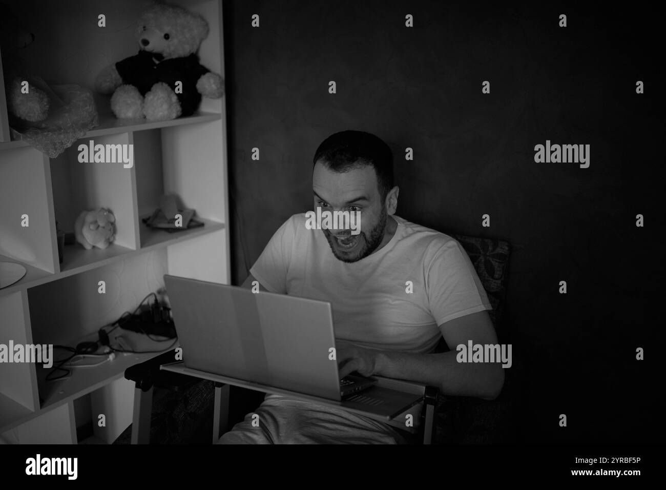 un homme de 30 ans est stressé lorsqu'il travaille sur un ordinateur portable depuis son bureau à domicile Banque D'Images