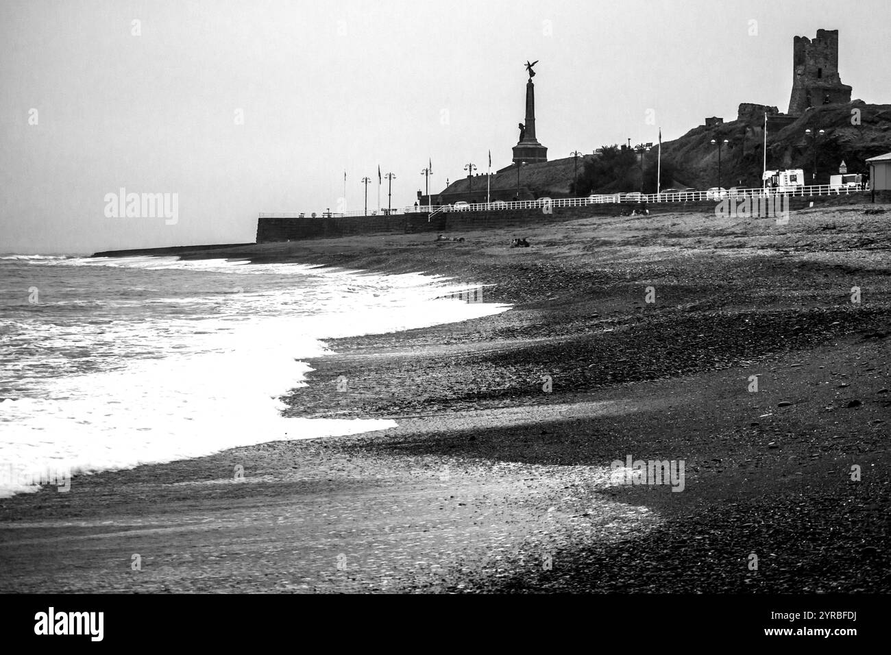 Côte noire et pleine d'esprit à Aberystwyth avec les ruines du château médiéval et le mémorial de la guerre mondiale en arrière-plan. Banque D'Images