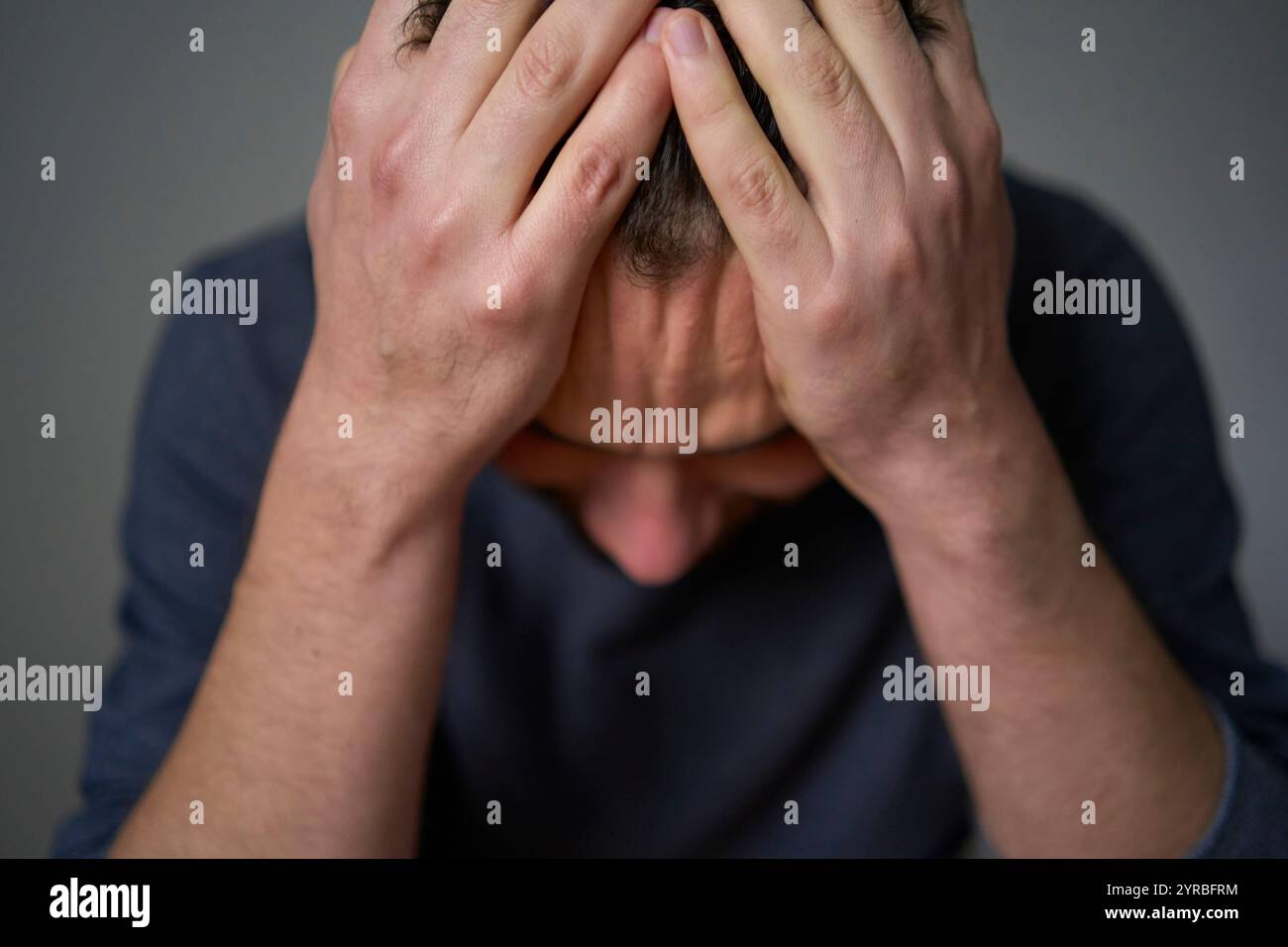 Un homme de 30 ans est stressé, tenant sa tête avec ses mains Banque D'Images