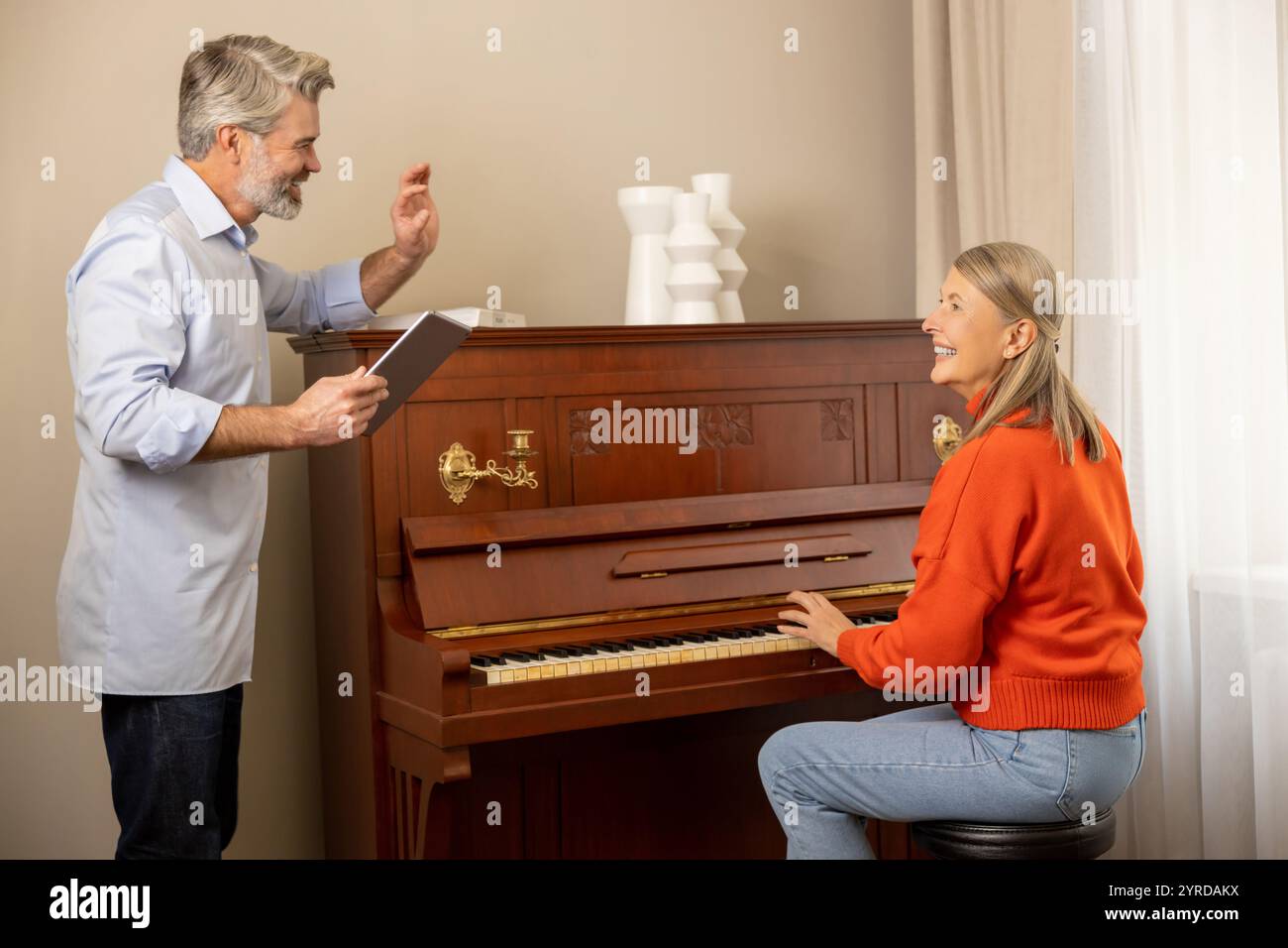 Musicien masculin enseignant à une femme à jouer du piano et expliquant quelque chose Banque D'Images