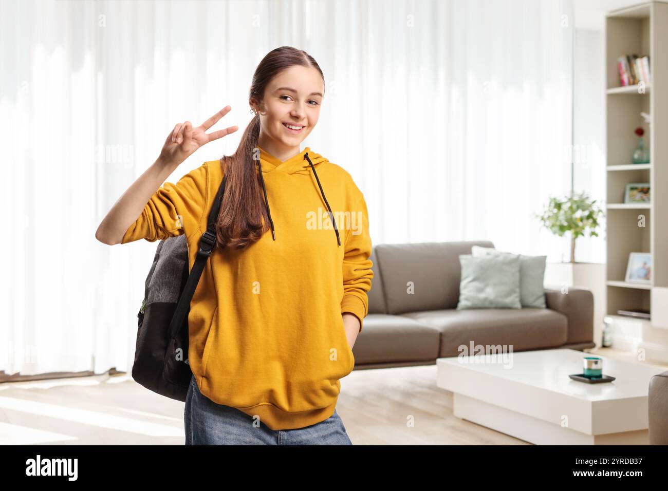 Adolescente gestuelle un signe de paix à la maison dans un salon Banque D'Images