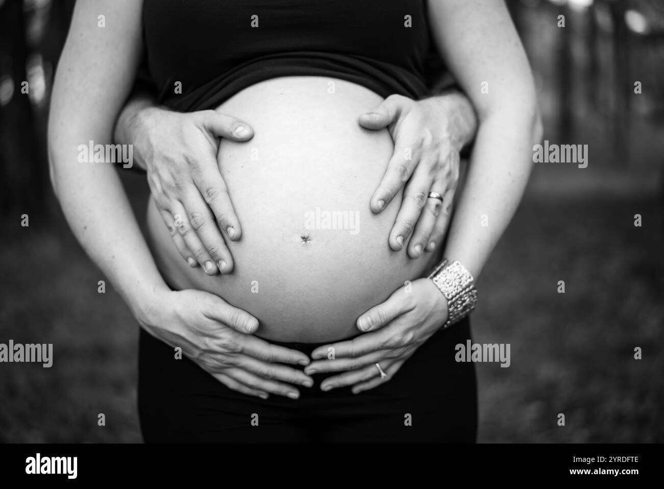Femme enceinte avec les mains sur le ventre à l'extérieur - Noir et Blanc Banque D'Images