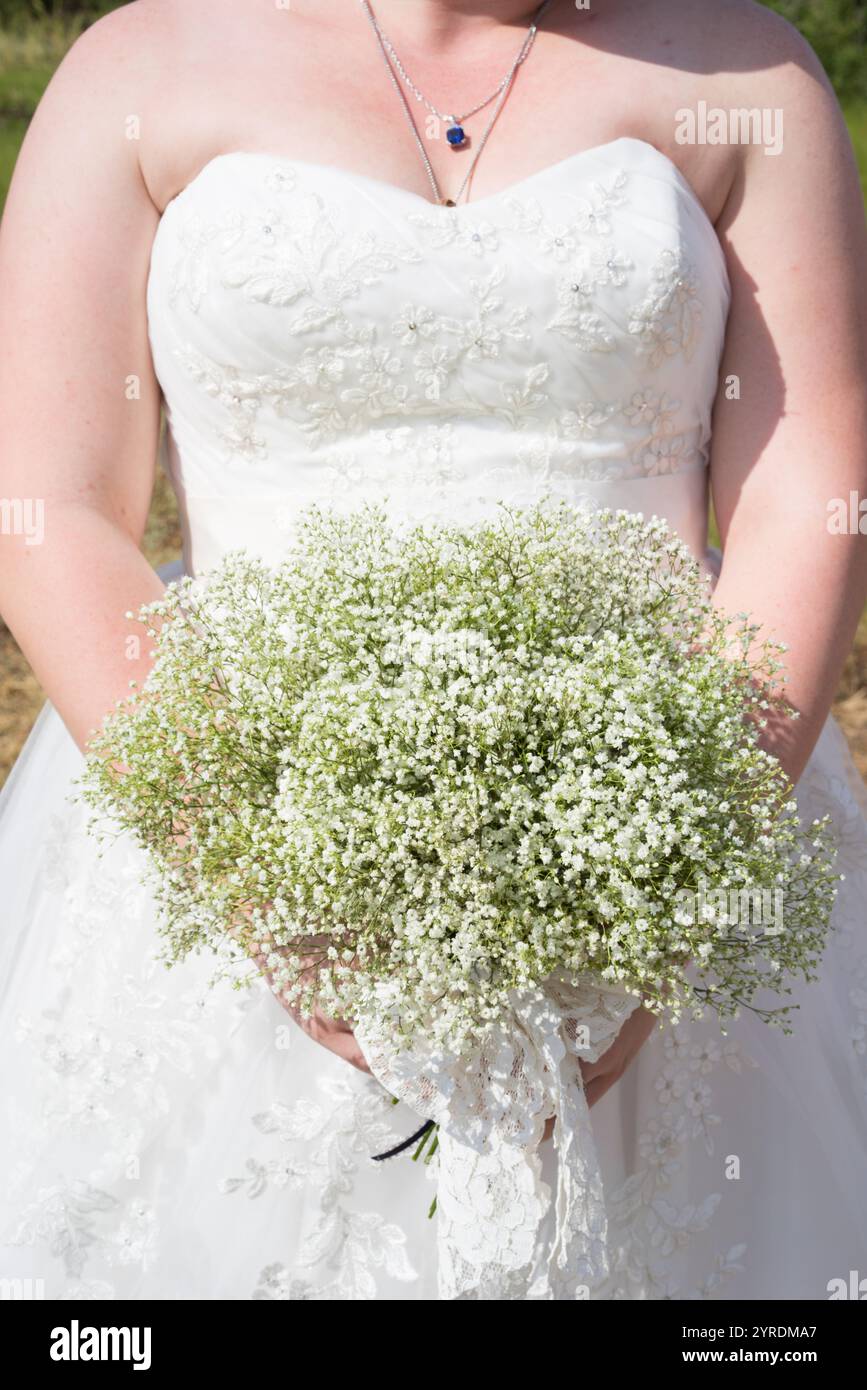 Gros plan de mariée tenant le bouquet Gypsophila dans la robe de mariée en dentelle blanche Banque D'Images