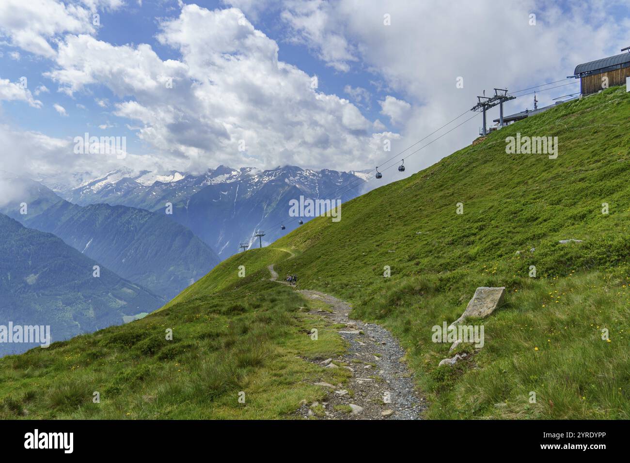 Sentier de randonnée sur une pente de montagne verdoyante avec téléphérique sous un ciel nuageux, mittersill, hohe tauern, autriche Banque D'Images