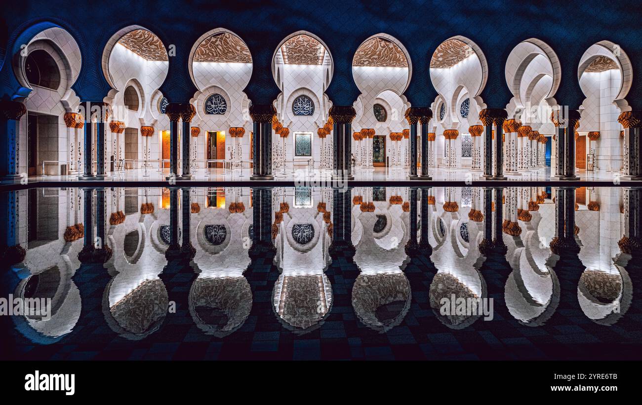 Colonnade illuminée de la Grande Mosquée Sheikh Zayed avec de superbes reflets dans la piscine de la cour la nuit, Abu Dhabi, eau. Banque D'Images