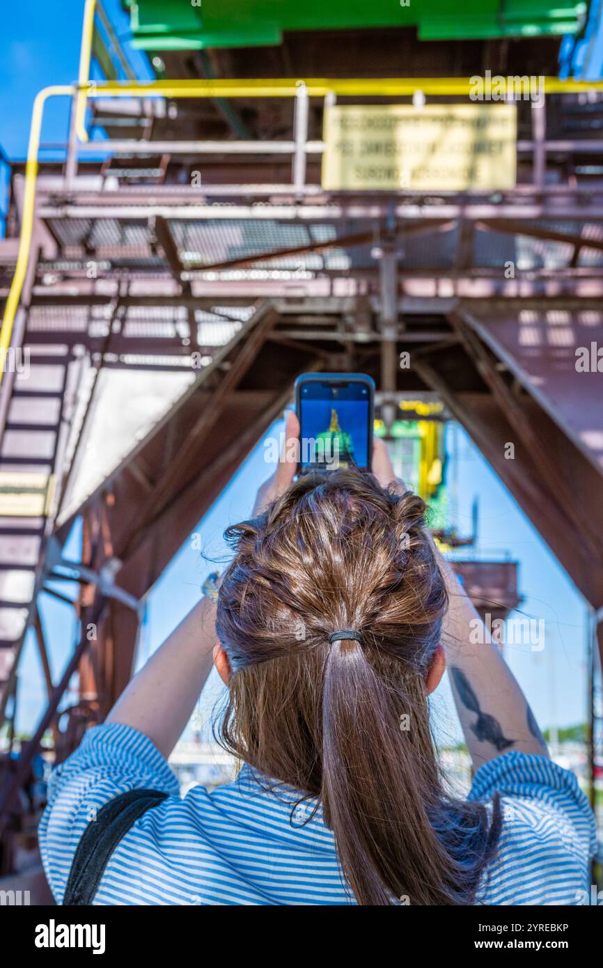 Touriste prenant une photo d'une ancienne grue portuaire, dzwigozaur, Szczecin, Pologne Banque D'Images