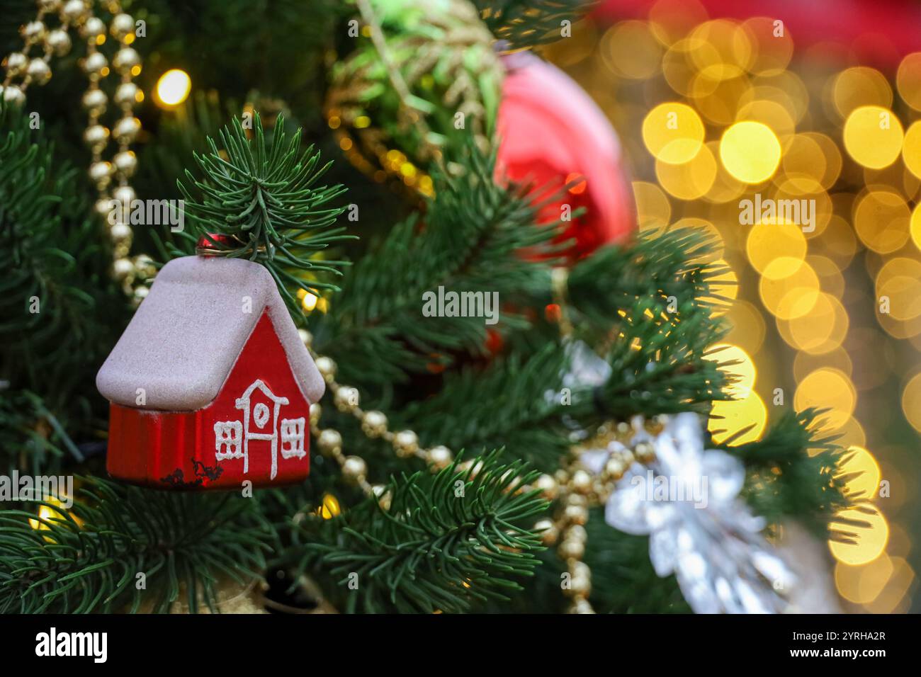 Célébration du nouvel an, branches d'arbre de Noël avec maison de jouet sur fond de lumières dorées Banque D'Images