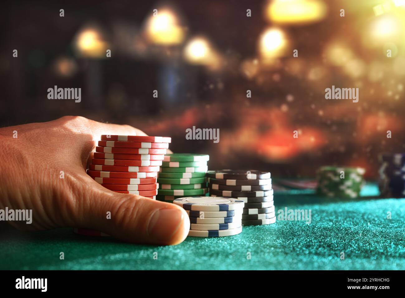 Jetons de jeu de Paris à la main sur tapis de feutre vert avec salle de jeu en arrière-plan. Vue de face. Banque D'Images