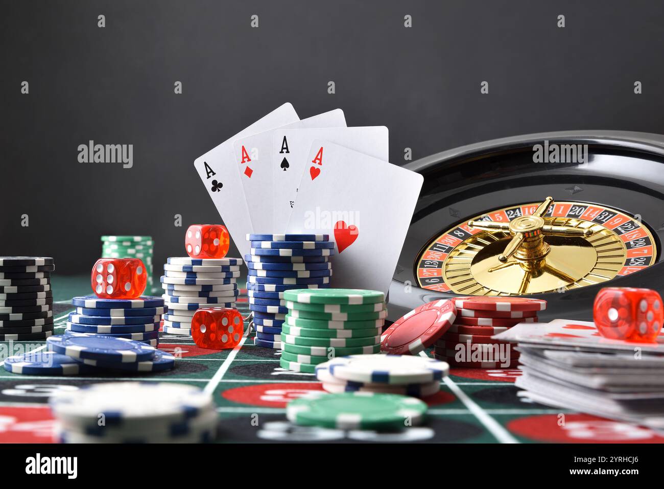 Détail de la table de jeu de casino avec tapis de jeu avec des piles de jetons de pari sur les nombres et la roulette, les cartes et les dés avec fond sombre de la salle de jeu W Banque D'Images