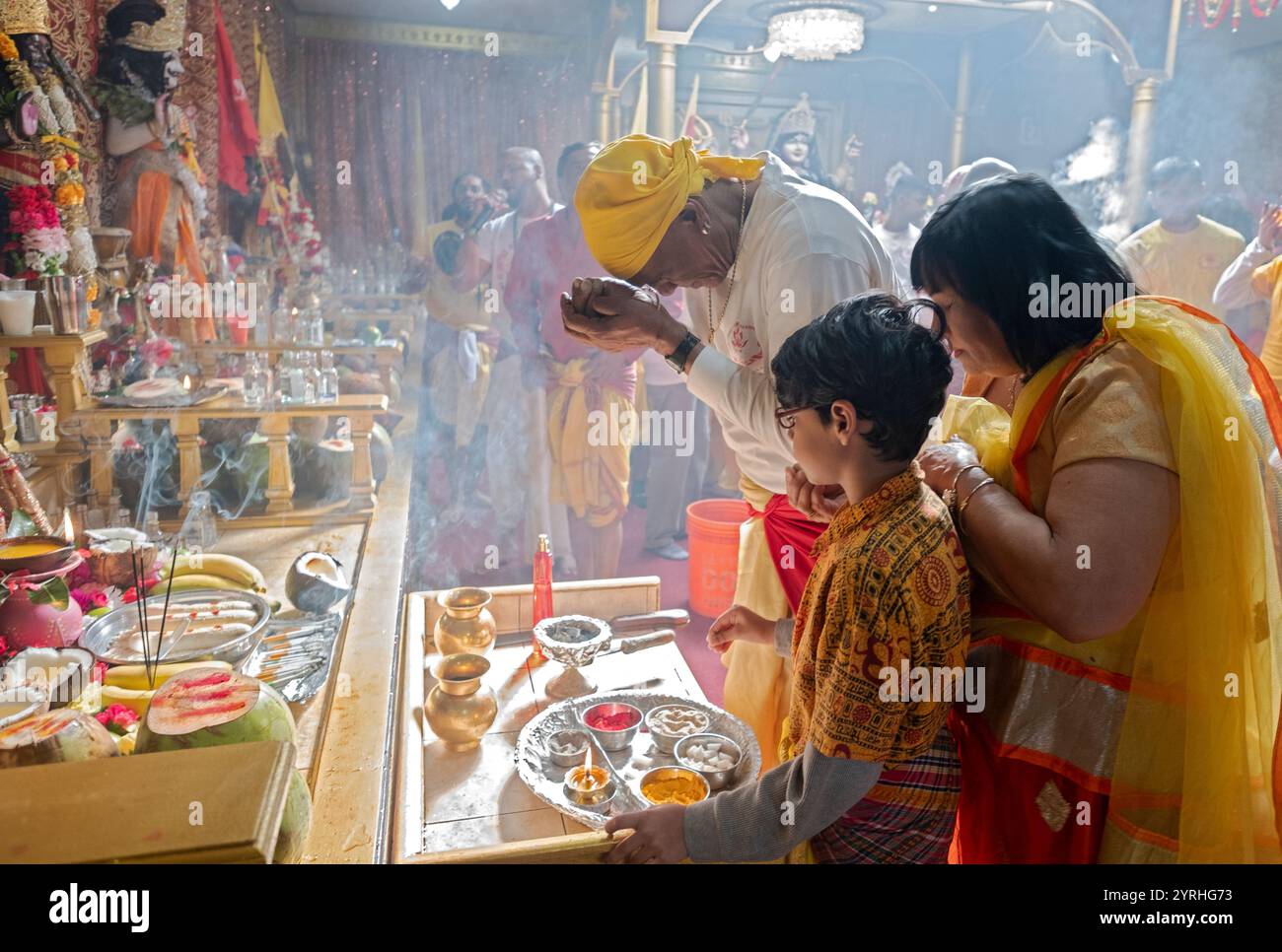 Les fidèles hindous présentent des offrandes à leurs divinités dans un temple de South Queens, New York. Banque D'Images