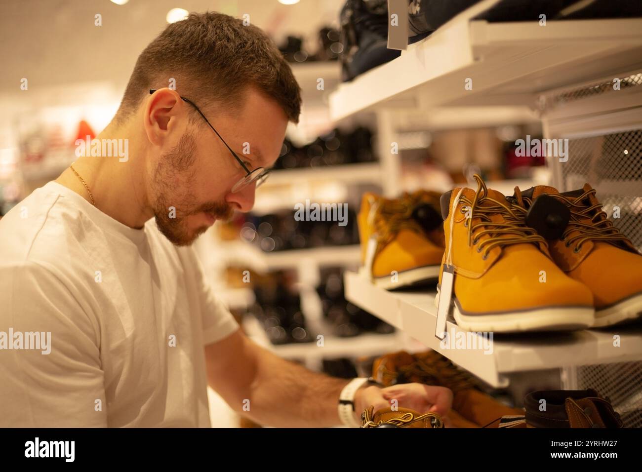 Un homme regarde des chaussures et des vêtements dans un magasin Banque D'Images