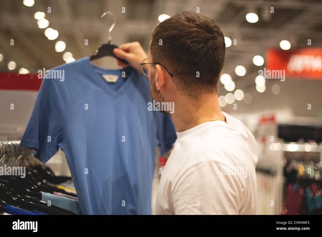 Un homme regarde des chaussures et des vêtements dans un magasin Banque D'Images