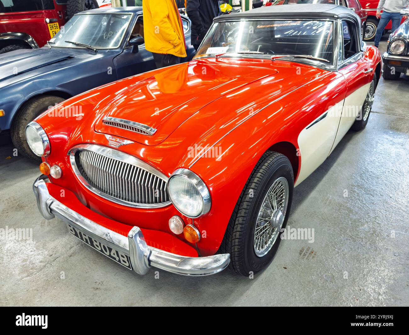 Vue de face d'une voiture de sport rouge Austin Healey 3000 MK 3 classique avec une plaque d'immatriculation vintage dans un cadre d'exposition automobile intérieure - Image de stock capturée avec un smartphone
