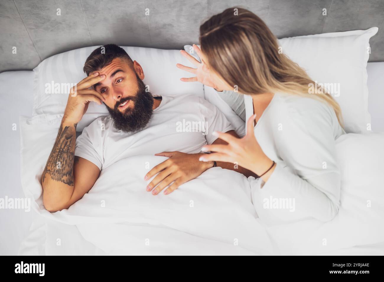 Le couple est allongé dans son lit et se dispute. La femme est en colère contre l'homme. Banque D'Images