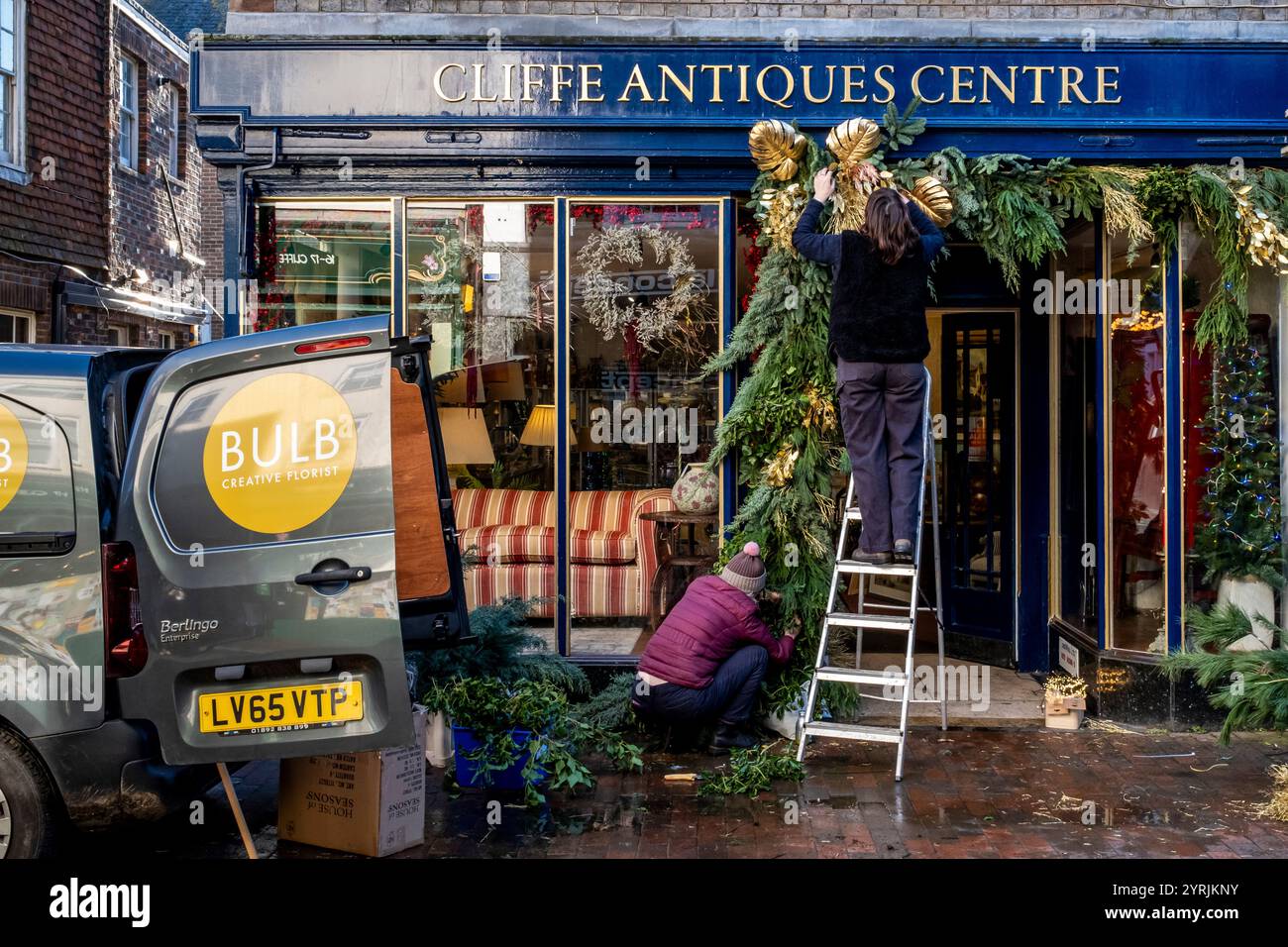 Les gens mettent en place des décorations de Noël devant un magasin d'antiquités dans la High Street, Lewes, East Sussex, Royaume-Uni. Banque D'Images