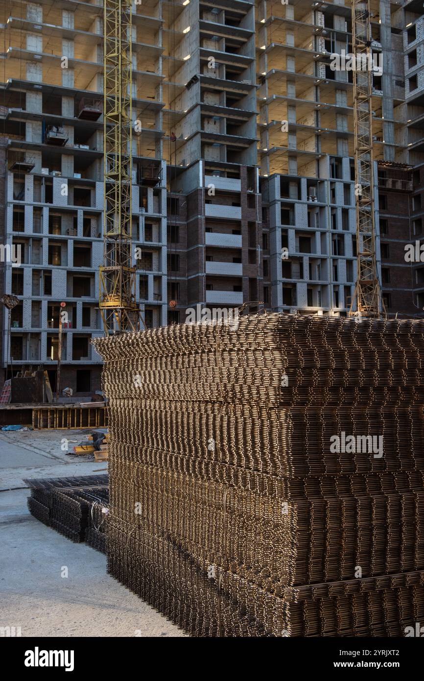Construction en cours d'appartements modernes de grande hauteur avec grues, renforts en acier et structures inachevées. Banque D'Images