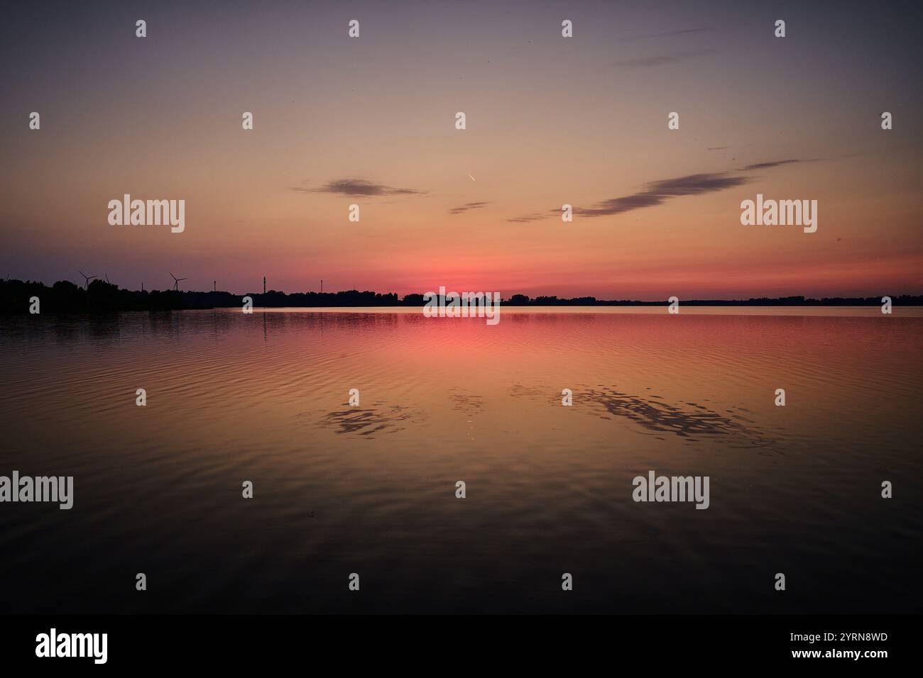 Un coucher de soleil serein sur un lac tranquille, reflétant des tons roses et violets doux à la surface de l'eau. Banque D'Images