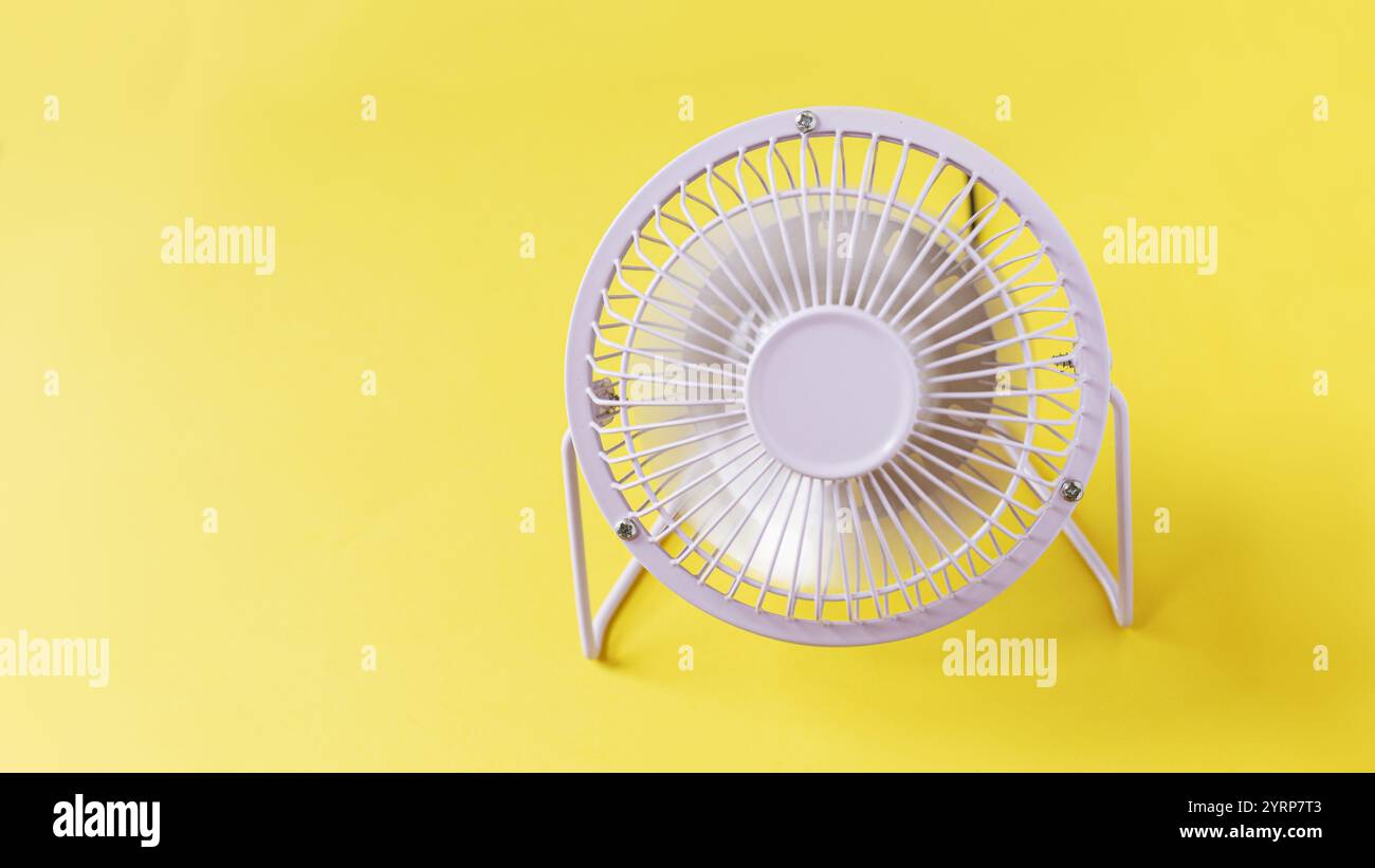 ventilateur en métal se tient sur un fond jaune et souffle. Chaleur et flux d'air, créatif Banque D'Images