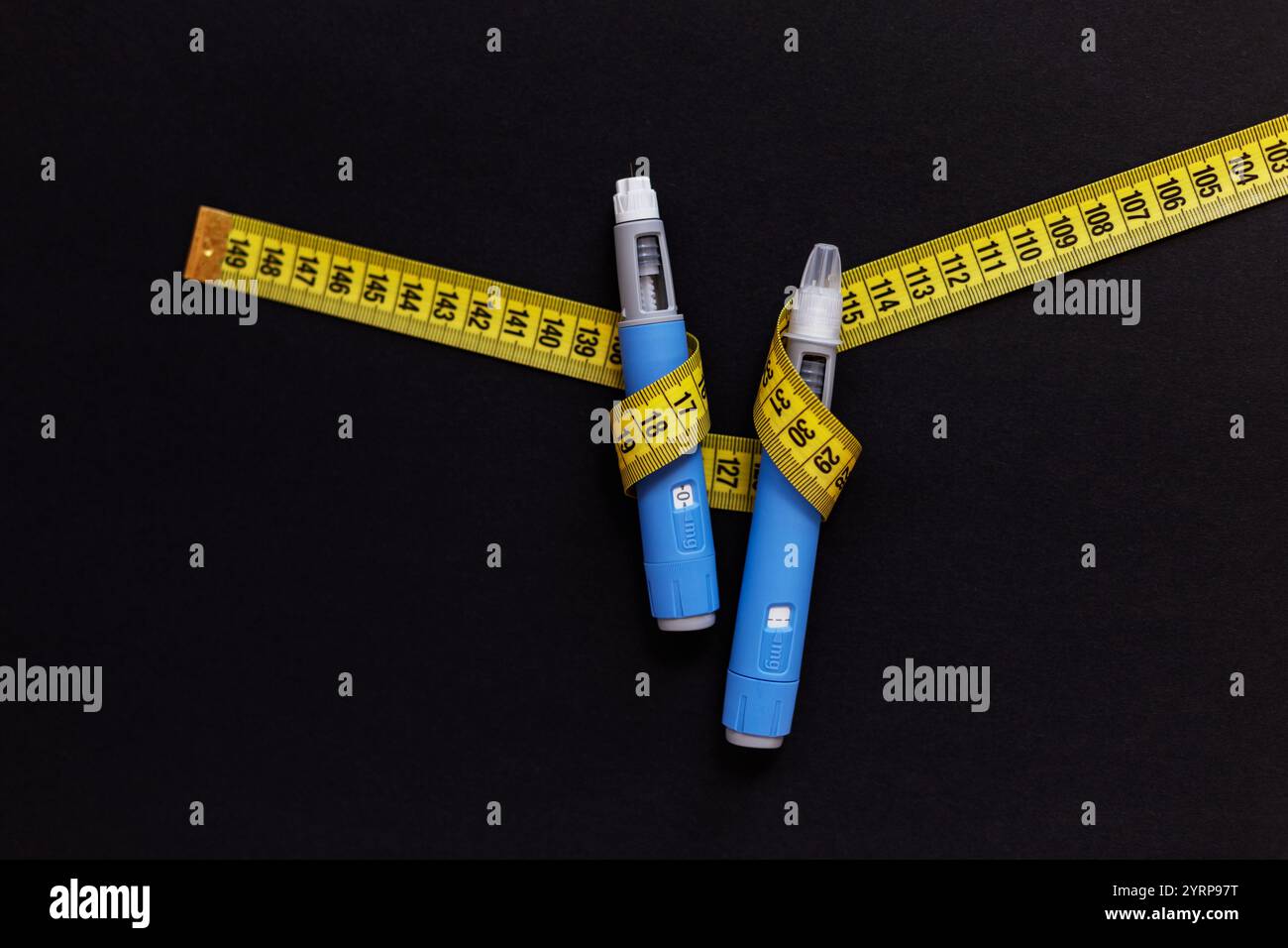 Injection de deux drogues ozempic pour la perte de poids avec un ruban à mesurer jaune sur fond noir. Stylos chacun d'un médicament fictif Semiglutin utilisé pour nous Banque D'Images