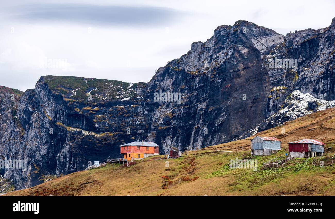 Maisons de plateau au sommet de la montagne. Roches noires et ciel en arrière-plan. Cabanes dans la verdure. Banque D'Images