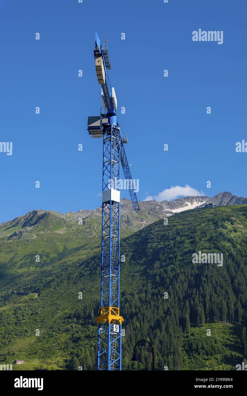 Grue de construction et Alpes suisses avec ciel bleu clair et lumière du soleil à Andermatt, Uri, Suisse. Banque D'Images