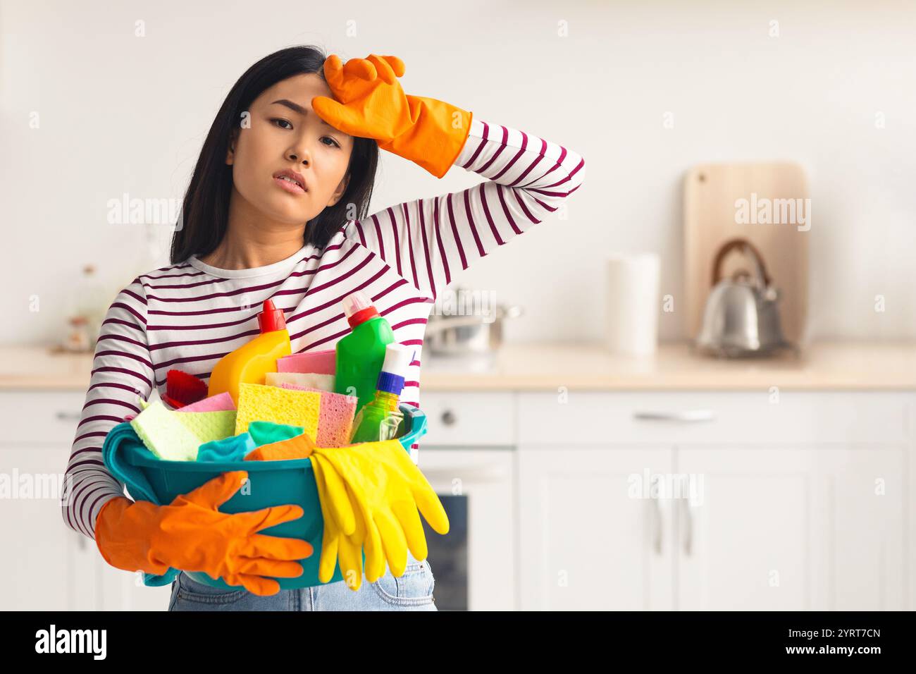 Femme asiatique travaillant dur avec busket plein de fournitures de nettoyage Banque D'Images