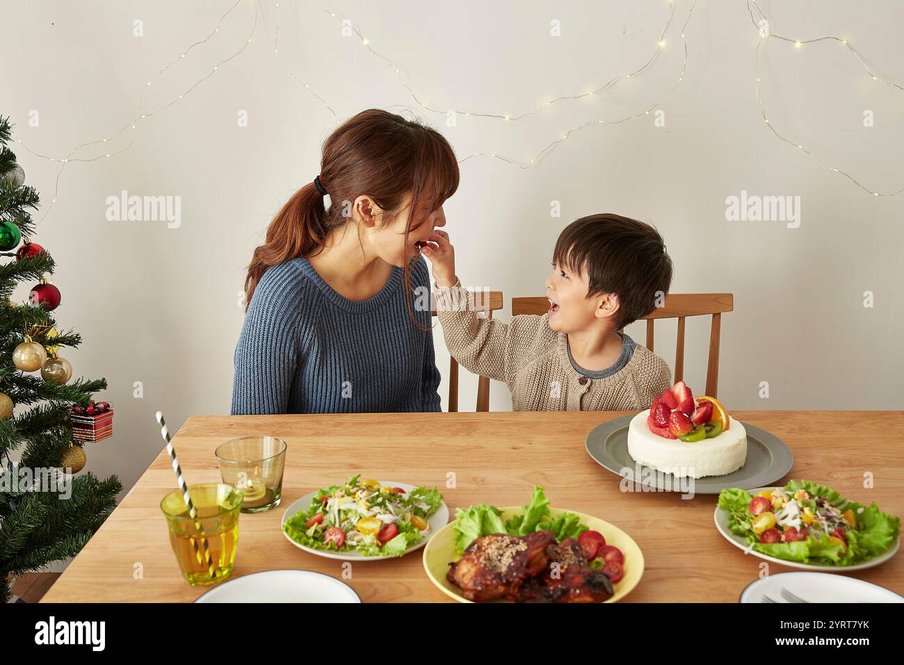 Garçon nourrissant des fraises d'un gâteau à sa mère à une fête de Noël Banque D'Images