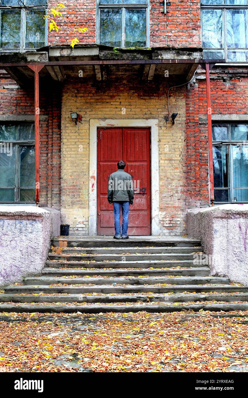 homme debout devant la vieille maison avec porte fermée Banque D'Images