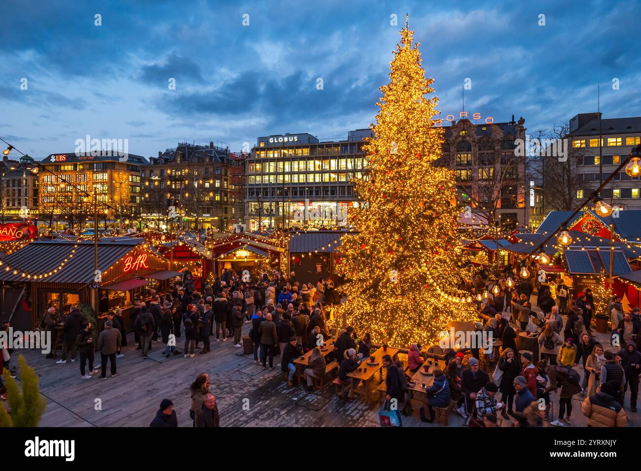 3-12-2024 Zurich, Suisse. Les gens visitent les boutiques pop-up au marché de Noël Sechselautenplatz. Heure bleue tard le soir, lumières de Noël. Banque D'Images