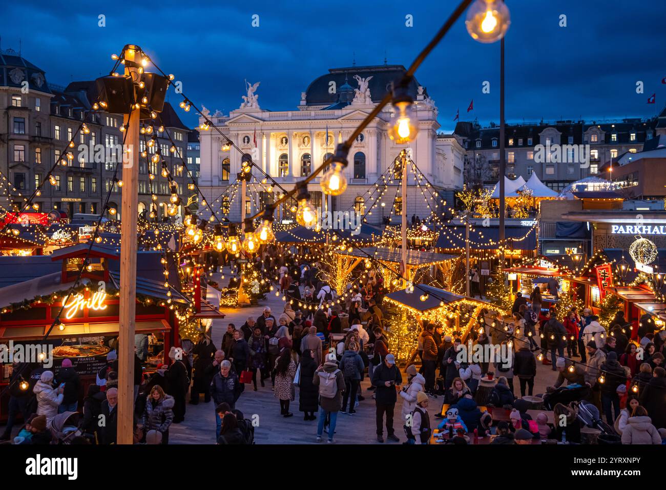 3-12-2024 Zurich, Suisse. Les gens visitent les boutiques pop-up au marché de Noël Sechselautenplatz. Heure bleue tard le soir, lumières de Noël. Banque D'Images