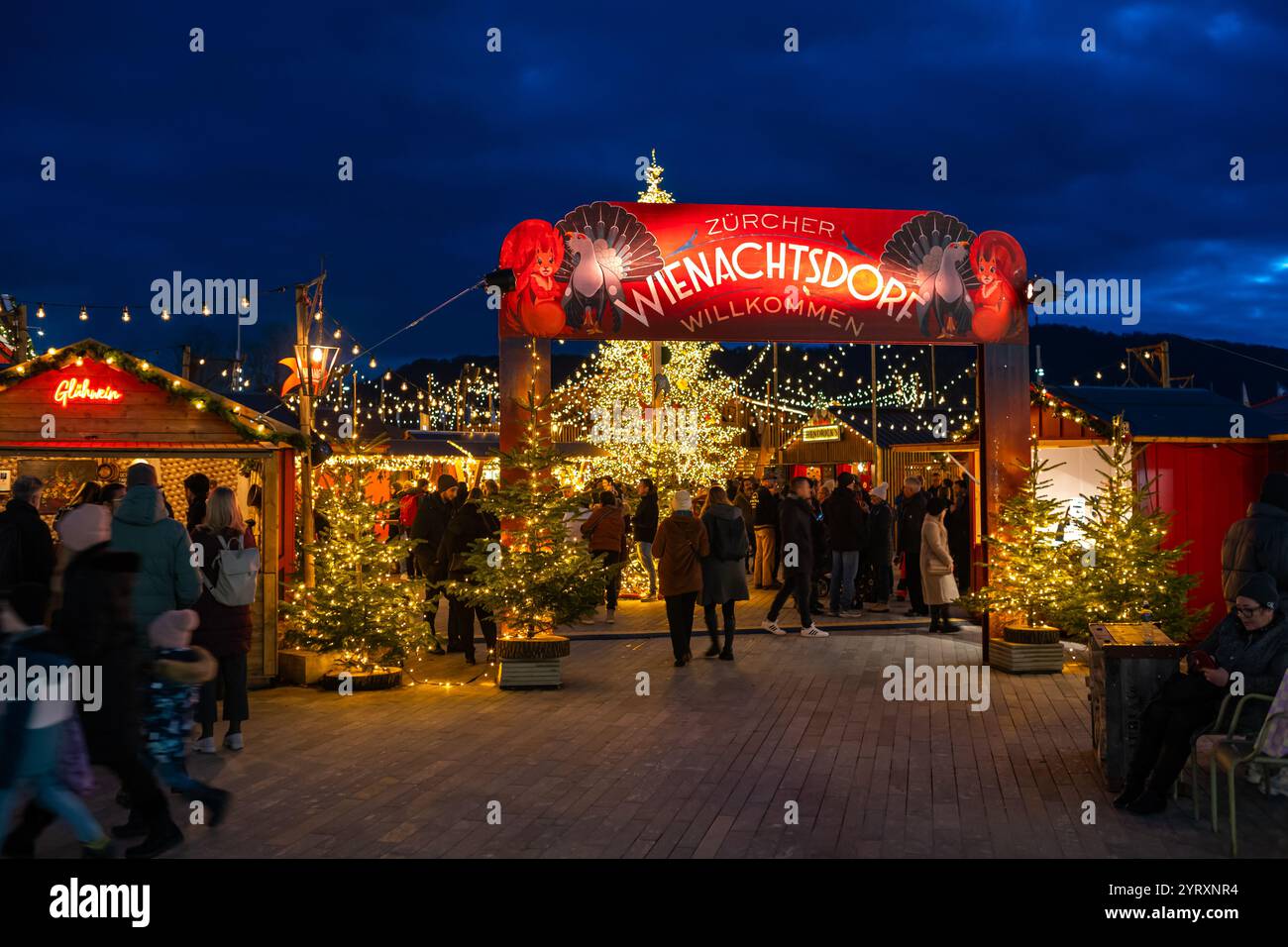 3-12-2024 Zurich, Suisse. Les gens visitent les boutiques pop-up au marché de Noël Sechselautenplatz. Heure bleue tard le soir, lumières de Noël. Banque D'Images