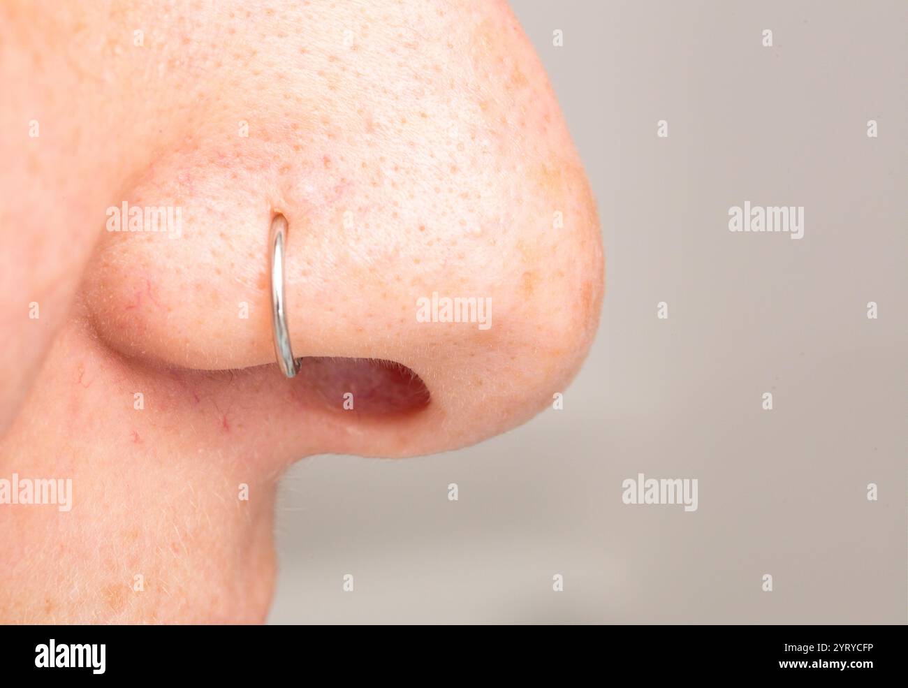 Gros plan d'un nez avec un anneau piercing en argent, mettant en évidence la modification du corps et le style personnel Banque D'Images