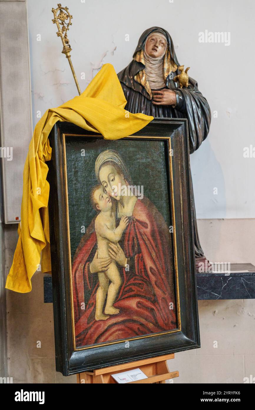 Peinture religieuse antique de la Vierge Marie avec l'enfant Jésus exposé à côté d'une statue de saint, reflétant l'art sacré et la dévotion historique. Banque D'Images