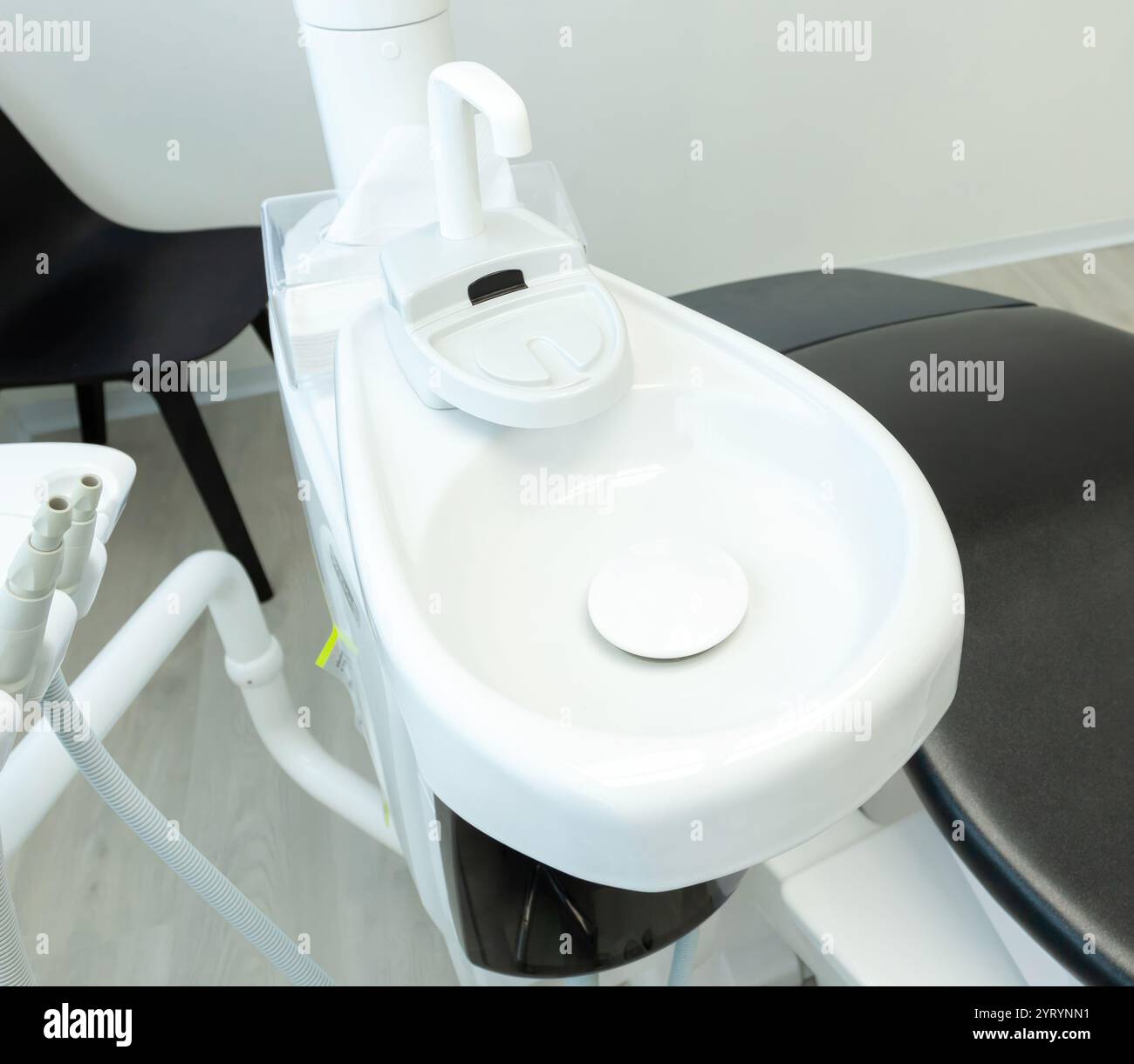 Évier blanc avec robinet et porte-gobelet d'un fauteuil de dentiste dans une clinique dentaire, prêt pour le rinçage Banque D'Images
