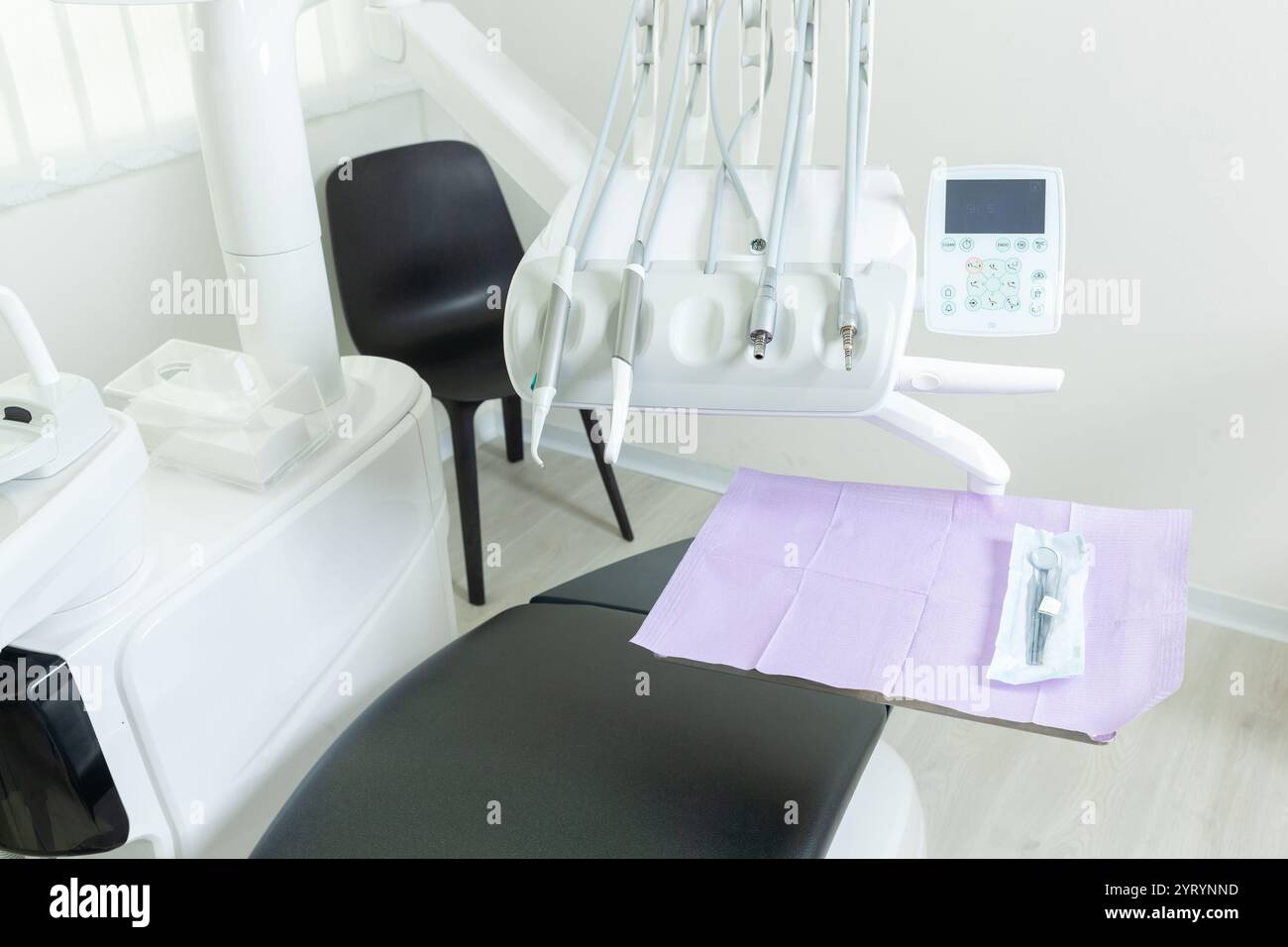 Instruments dentaires suspendus au-dessus d'une chaise de patient dans une clinique dentaire moderne, prêts pour le prochain patient Banque D'Images