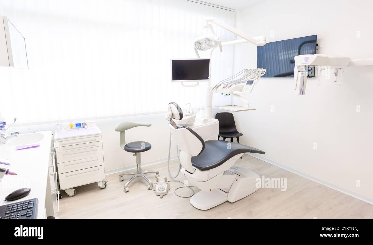 Clinique dentaire vide montrant l'équipement moderne, y compris un fauteuil dentaire, un moniteur et d'autres outils, prêts pour les patients Banque D'Images
