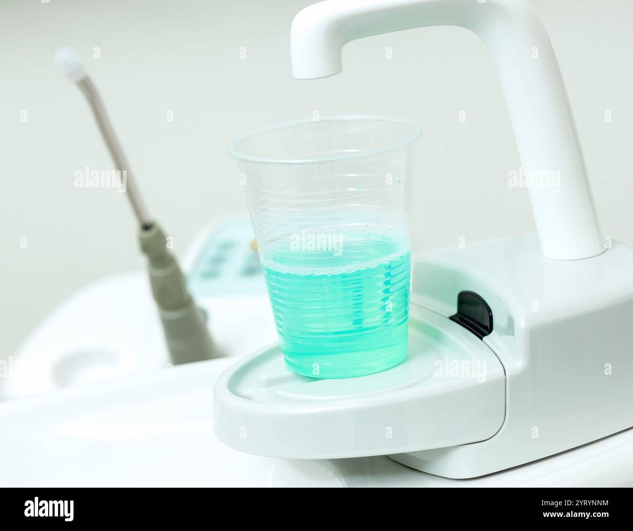 Équipement de clinique dentaire moderne distribuant un bain de bouche turquoise antiseptique dans une tasse jetable, favorisant la santé bucco-dentaire et l'hygiène Banque D'Images