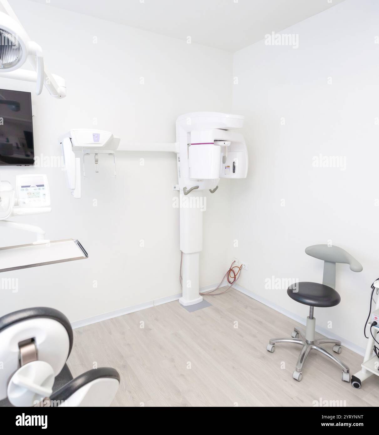 Intérieur d'une clinique dentaire moderne et lumineuse présentant un orthopantomographe, d'autres équipements spécialisés et un environnement propre et professionnel Banque D'Images
