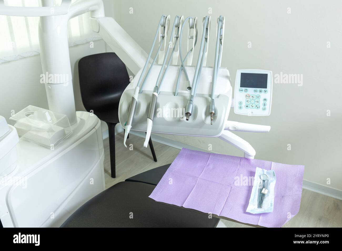 Instruments dentaires suspendus au-dessus de la chaise du patient, prêts pour un examen dentaire dans une clinique moderne, propre et bien équipée Banque D'Images