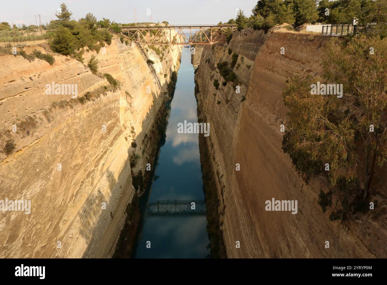 Le canal de Corinthe en Grèce relie le golfe de Corinthe dans la mer Ionienne au golfe Saronique dans la mer Égée. Il traverse l'étroit isthme de Corinthe et sépare le Péloponnèse du continent grec, faisant de la péninsule une île. Le canal mesure 6,4 kilomètres (4 miles) de long et seulement 24,6 mètres (80,7 pieds) de large au niveau de la mer. Le canal a été initialement proposé à l'époque classique et un effort infructueux a été fait pour le construire au Ier siècle après JC. La construction a repris en 1881 mais a été entravée par des problèmes géologiques et financiers qui ont ruiné les constructeurs originaux. C'était co Banque D'Images