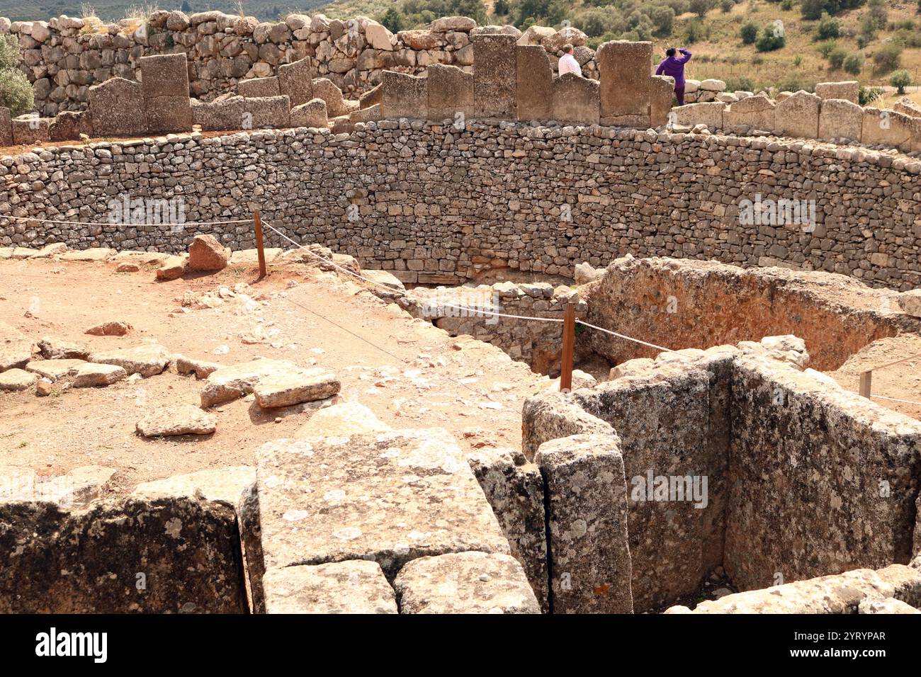 Grave Circle A est un cimetière royal du XVIe siècle av. J.-C. situé au sud de la porte du Lion, l'entrée principale de la citadelle de Mycènes de l'âge du bronze dans le sud de la Grèce. Ce complexe funéraire a été construit à l'extérieur des murs de Mycènes et finalement enfermé dans l'acropole lorsque la fortification a été étendue au cours du 13ème siècle av. J.-C. Représente l'une des caractéristiques significatives de la première phase de la civilisation mycénienne. Banque D'Images